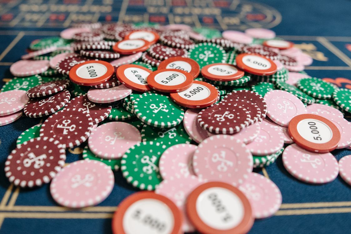 Chip poker nhiều màu xếp chồng trên bàn casino nỉ xanh